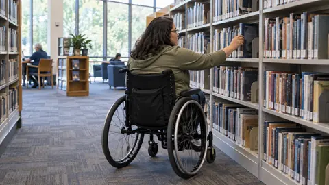 A wheelchair user browsing shelves in an accessible community library.