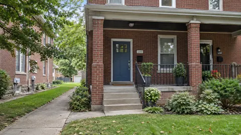 The entrance to a modest brick duplex with a small front yard.